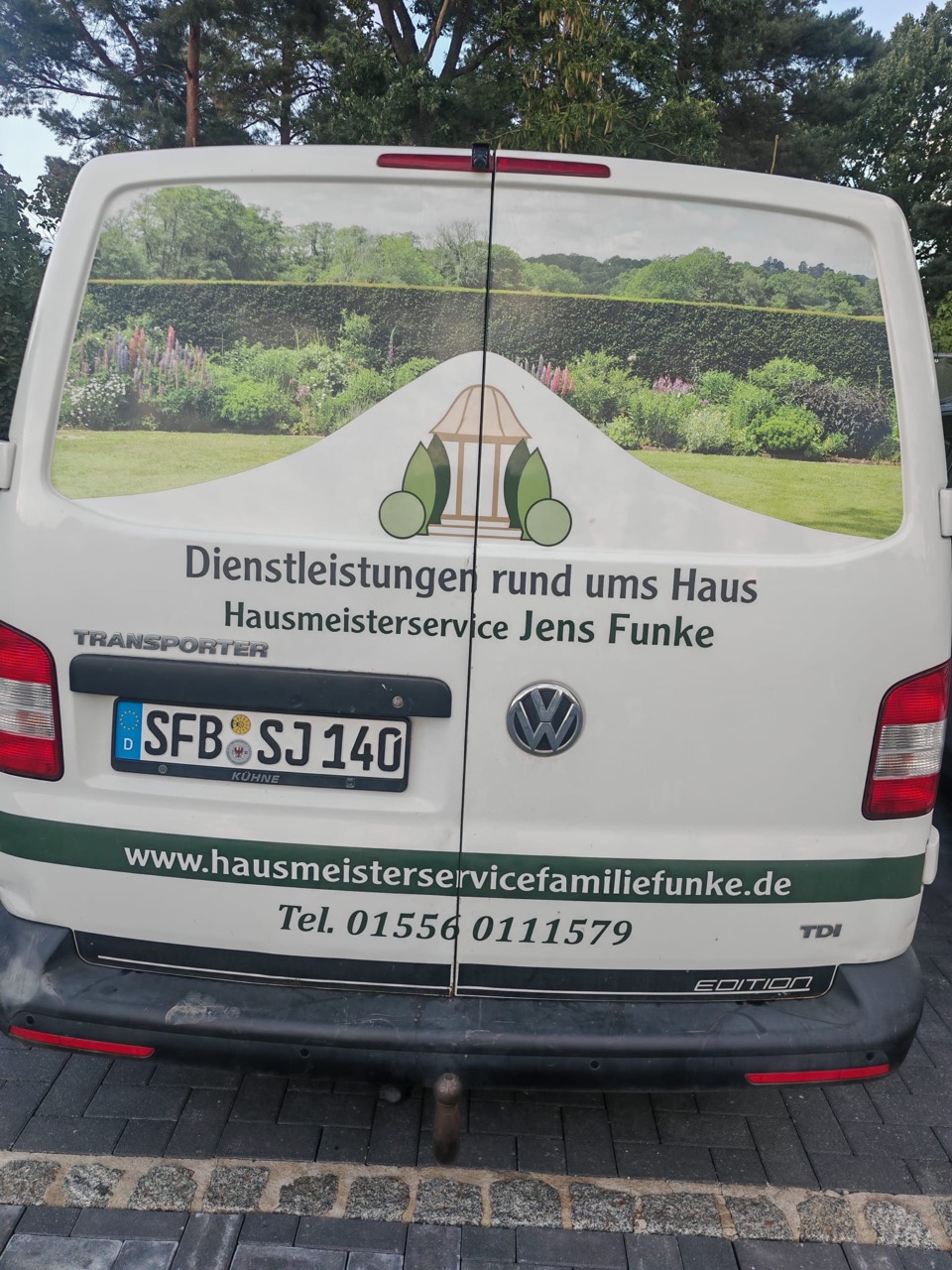Firmenfahrzeug des Hausmeisterservice Jens Funke mit grünem Gartenmotiv und Logo
